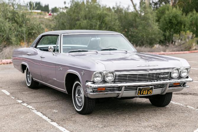 Вид спереди, 3 кв. ярда, на четырехдверный хардтоп Chevrolet Caprice Evening Orchid 1965 года с черным виниловым верхом и черным номерным знаком California