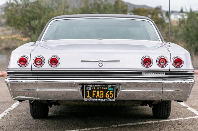 Вид сзади на четырехдверный хардтоп Chevrolet Caprice Evening Orchid 1965 года с черным виниловым верхом и черным номерным знаком California